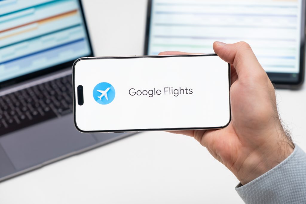 Homem segurando celular com Google Flights.
